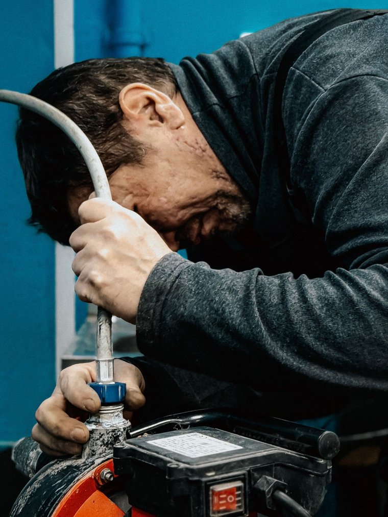 Technicien réglant une pompe électrique, tuyau raccordé